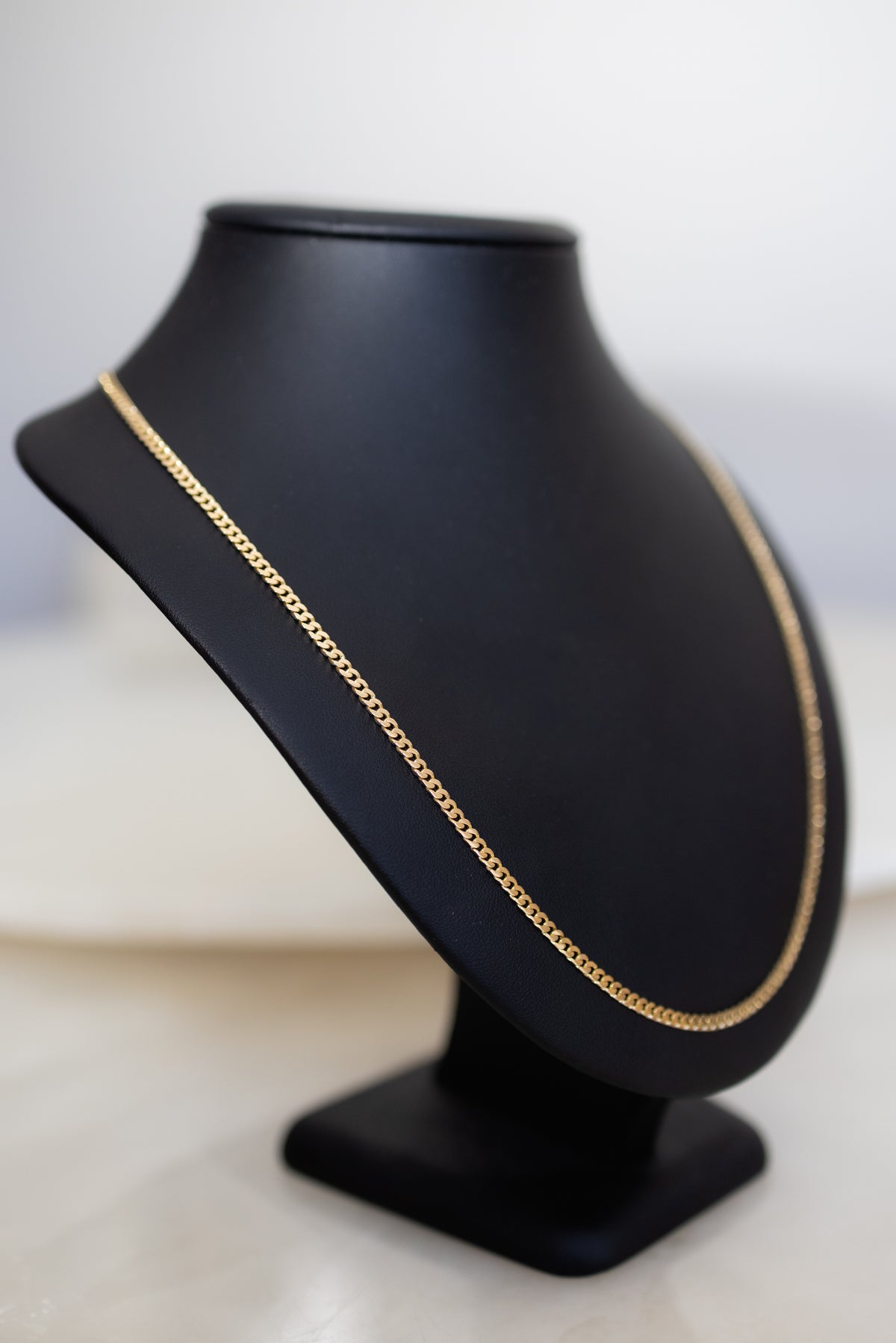 Angled view of the 18ct solid gold handmade Cuban link chain showing its depth and polish