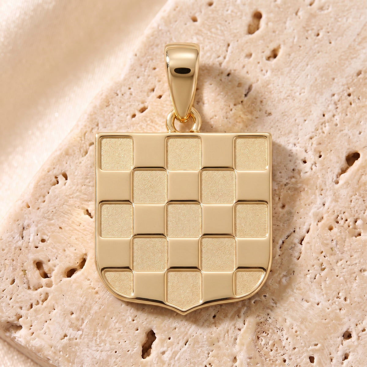 1990 GRB pendant in 9ct yellow gold resting on pale travertine stone
