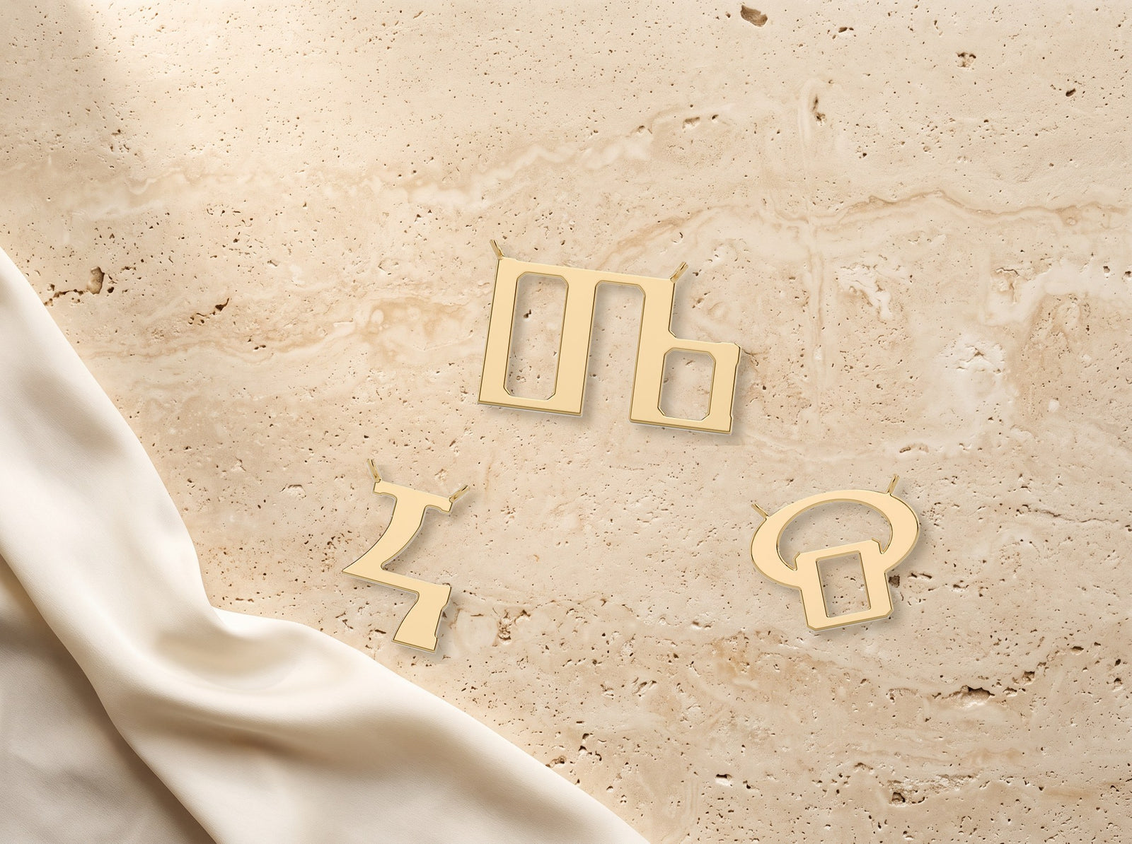 Glagolitic letters in 9ct yellow gold laid on travertine with ivory silk