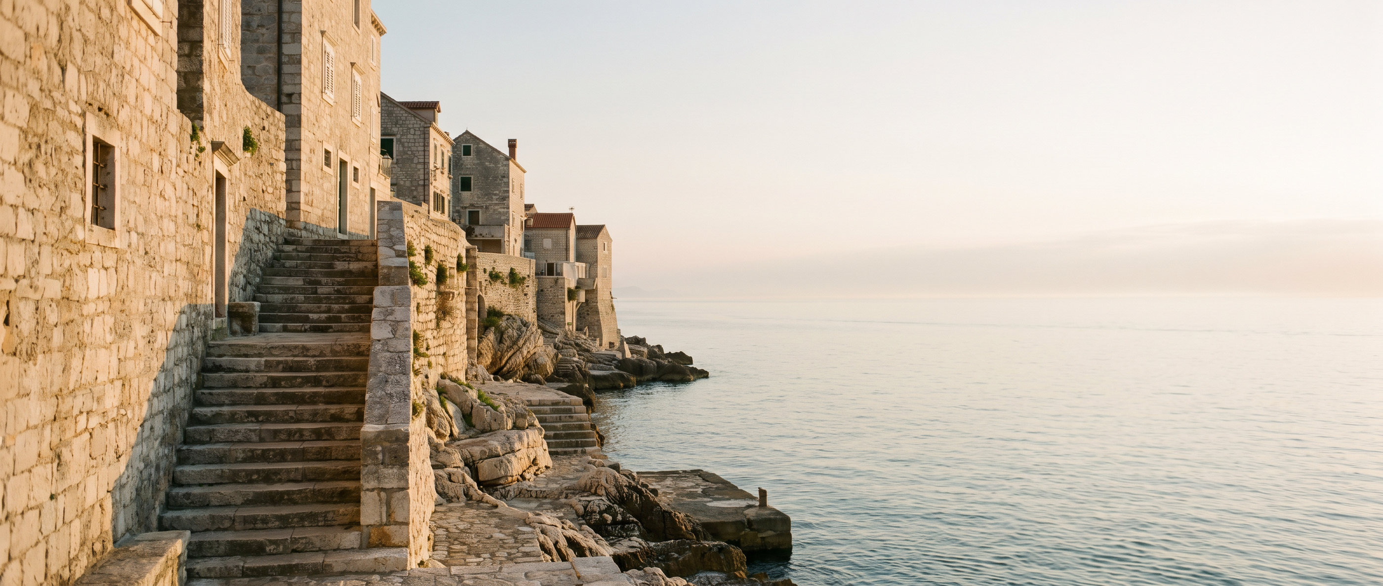Warm evening light on old Adriatic stone above a calm sea