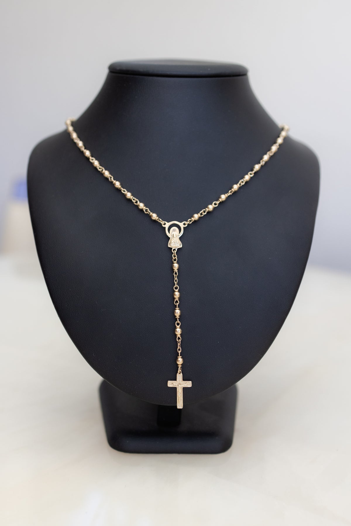 Solid 9ct gold rosary necklace seen front on, the crucifix hanging below the Marian centrepiece