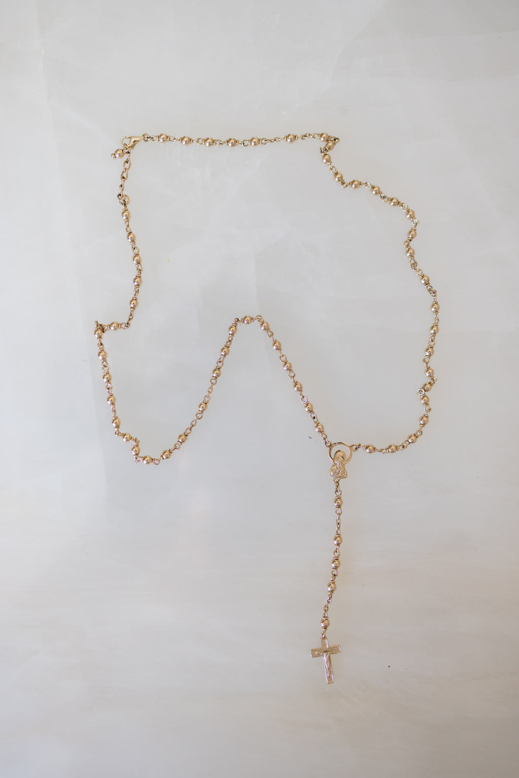 The complete 9ct gold rosary necklace laid flat on a white background
