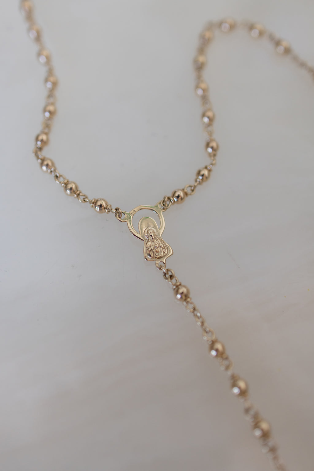 Flat lay detail of the Marian centrepiece and 4mm gold beads of the rosary