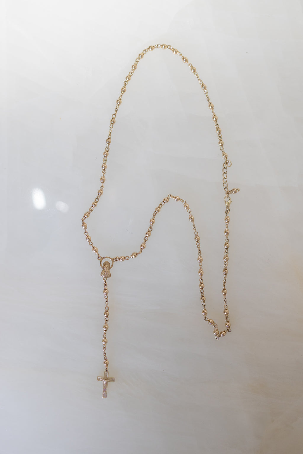 Full length of the 9ct gold rosary necklace laid flat, showing the 58cm to 61cm span