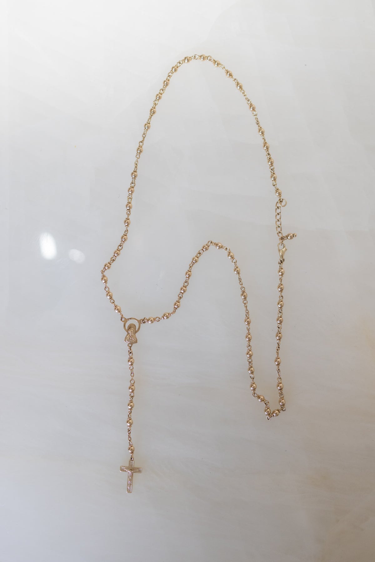 Full length of the 9ct gold rosary necklace laid flat, showing the 58cm to 61cm span