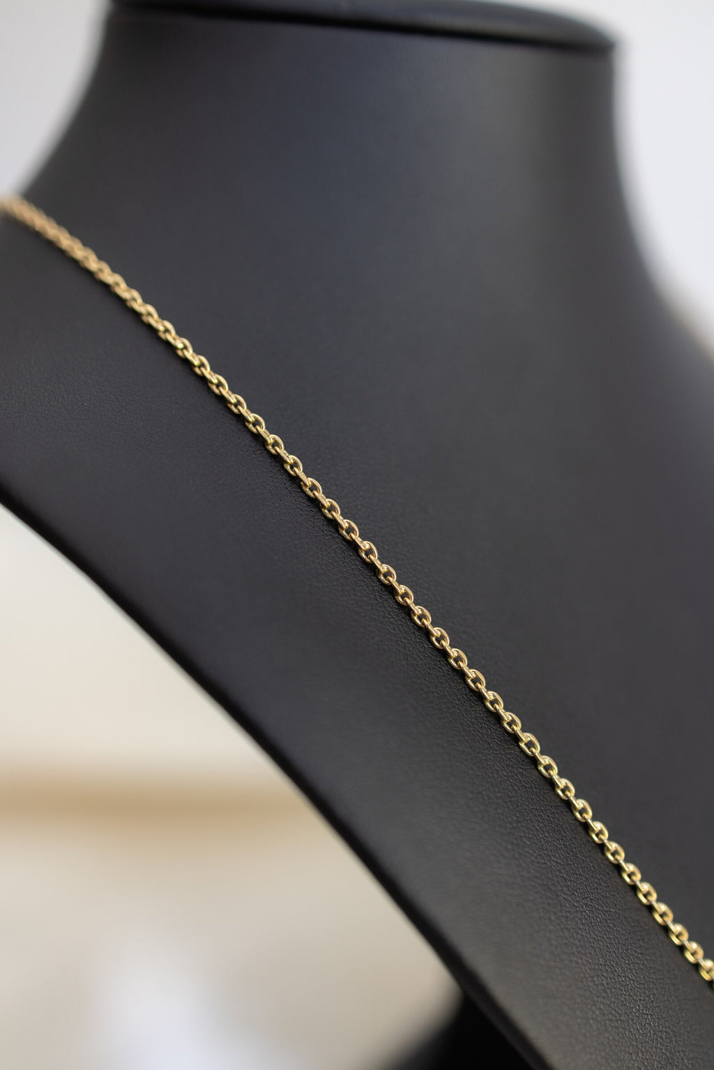 Angled view of the 1.7mm handmade 9ct yellow gold cable chain on a black bust