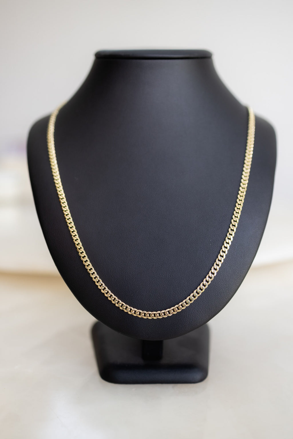Handmade 4.1mm Cuban link chain in 9ct yellow gold on a display bust, front view