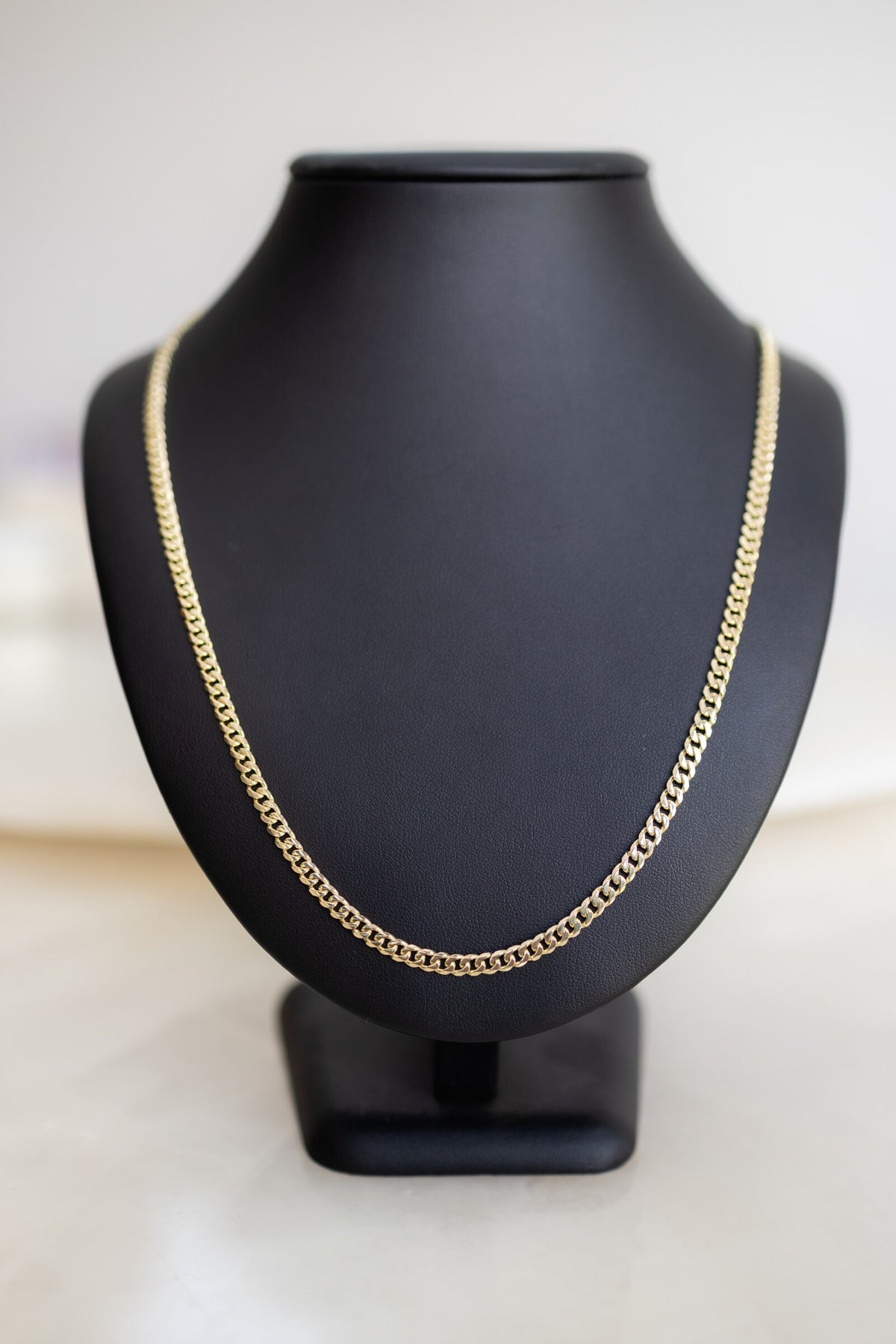 Handmade 4.1mm Cuban link chain in 9ct yellow gold on a display bust, front view
