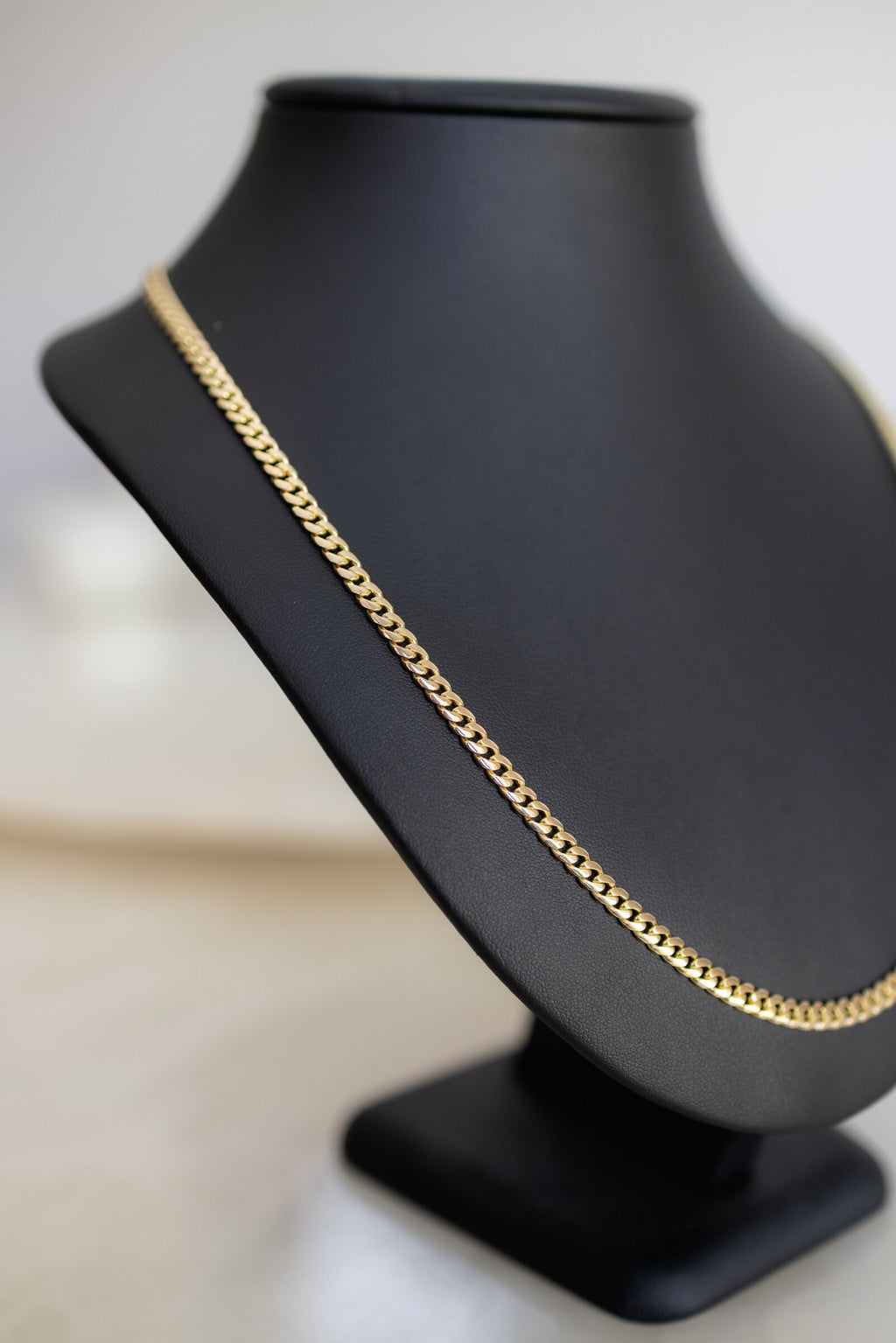 Handmade 4.4mm Cuban link chain in 9ct yellow gold, angled view on a bust