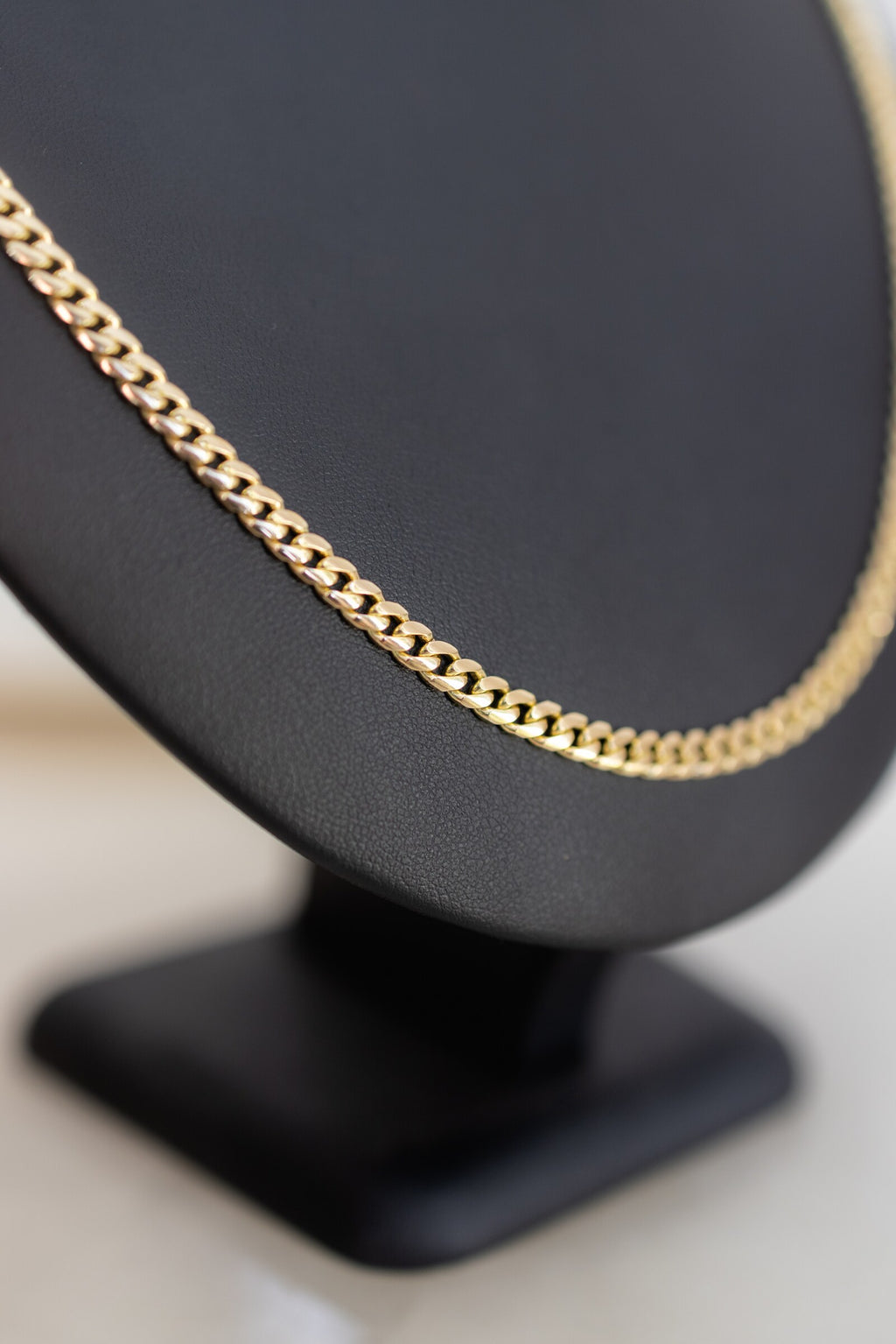 9ct yellow gold 4.4mm Cuban link chain curving over the shoulder of a display bust