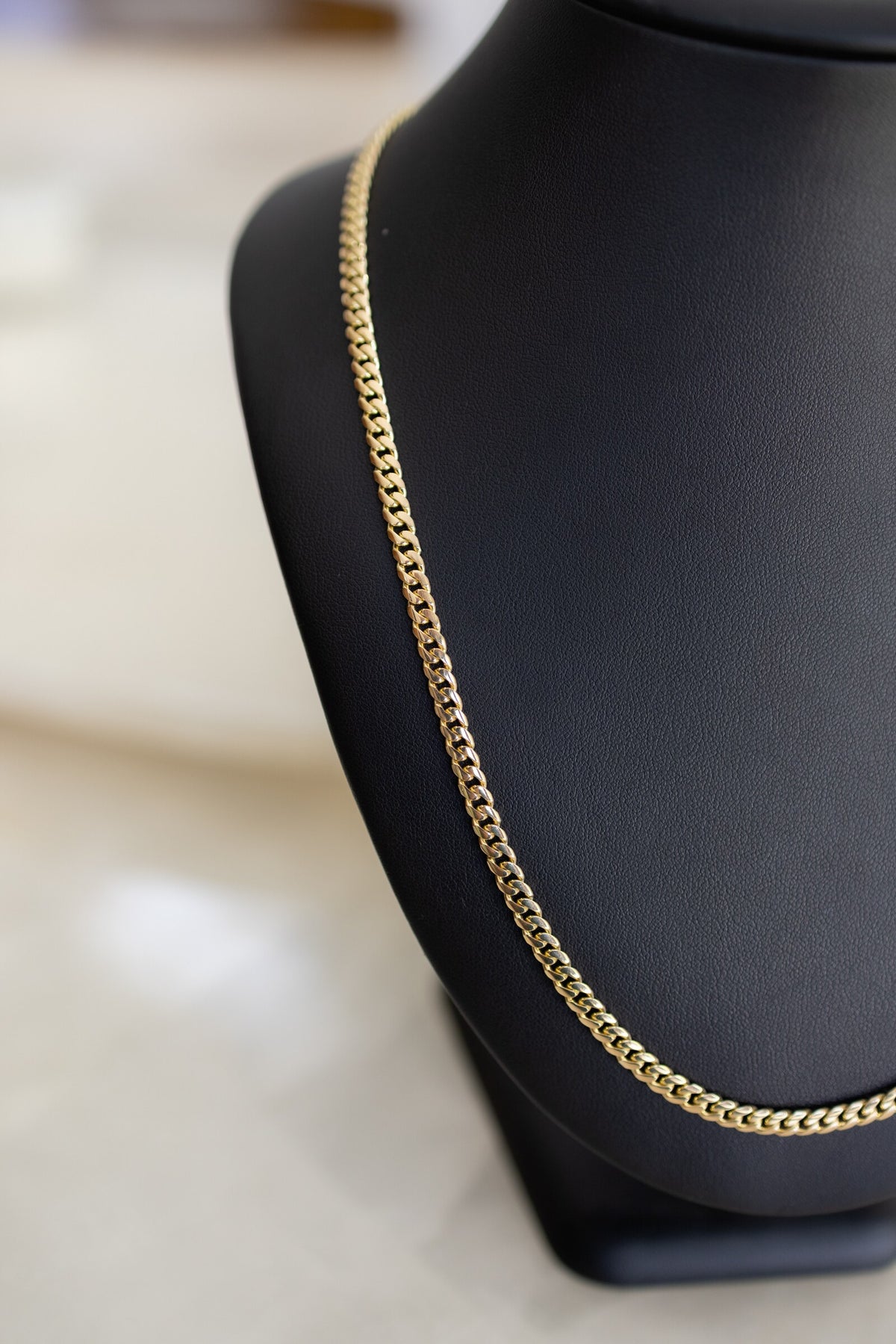 4.4mm handmade Cuban link chain in 9ct yellow gold against a black leather bust
