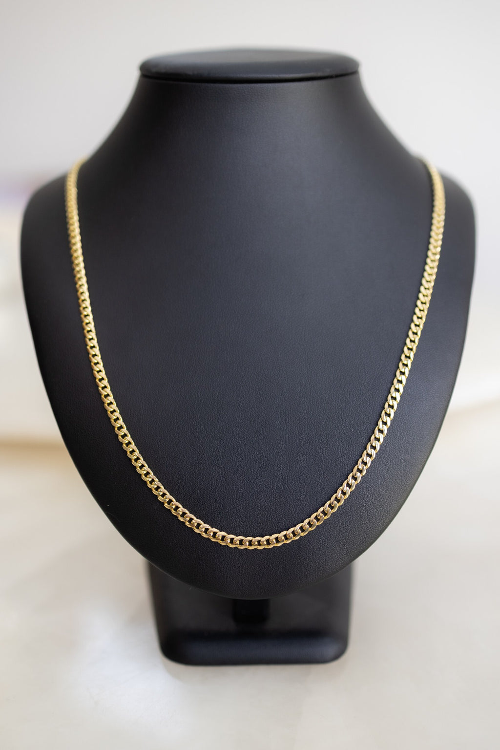 Handmade 4mm Cuban link chain in 9ct yellow gold on a display bust, front view