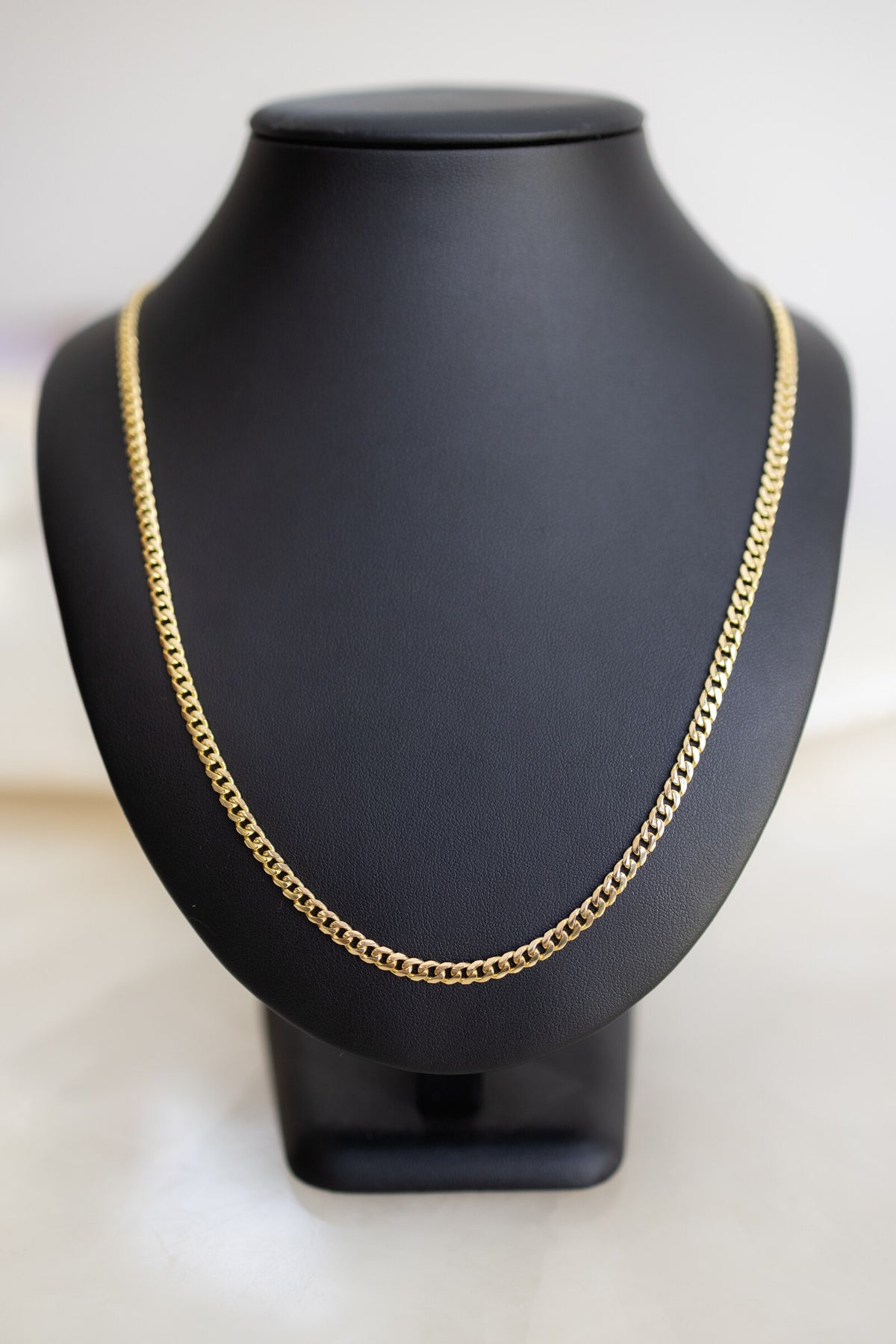 Handmade 4mm Cuban link chain in 9ct yellow gold on a display bust, front view
