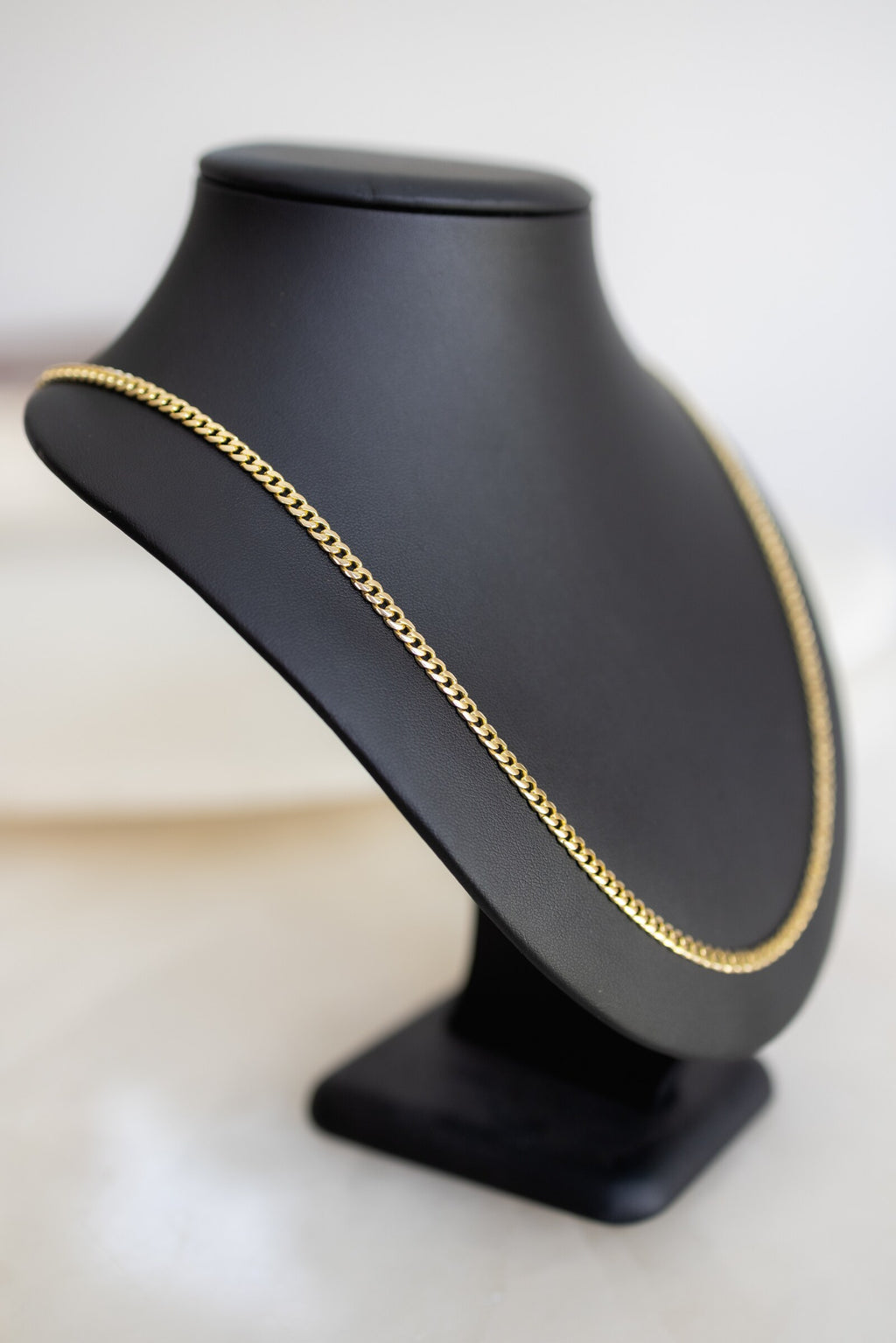 4mm 9ct yellow gold handmade Cuban link chain shown on an angled display bust