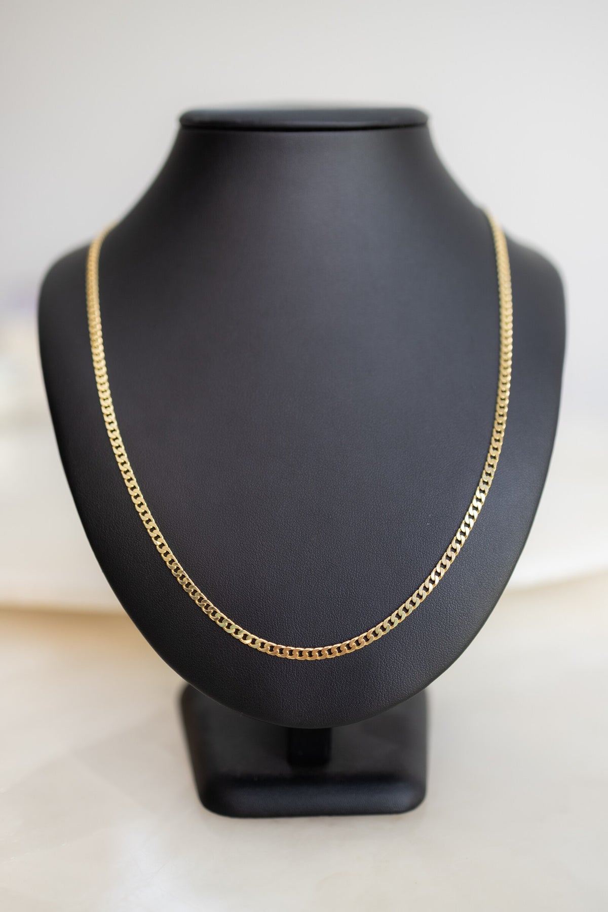 Italian made 3mm Cuban link chain in 9ct yellow gold on a display bust, front view
