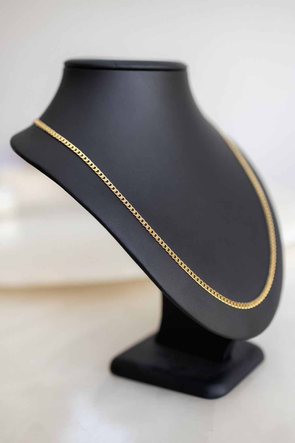 Italian made 3mm Cuban link chain in 9ct yellow gold, angled view on a bust